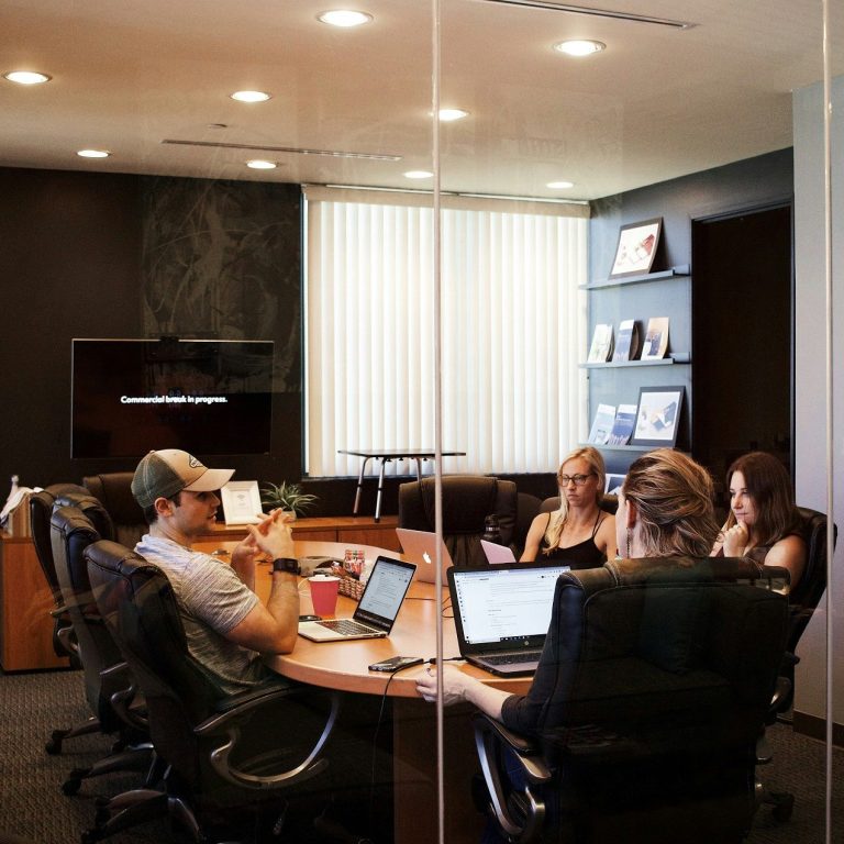 Grupo de personas en una sala de reuniones, trabajando en laptops y documentos. Grupo de personas en una sala de reuniones, trabajando en laptops y documentos.